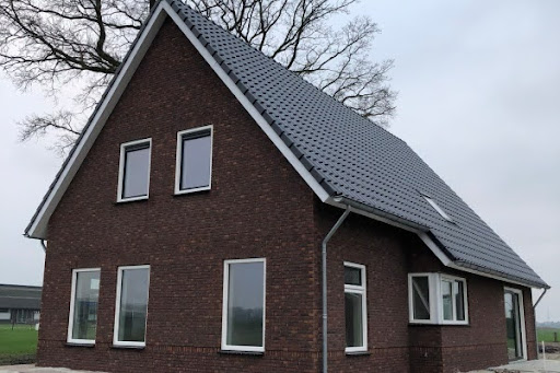 Moderne nieuwbouwwoning met donkerbruine stenen en witte kozijnen.