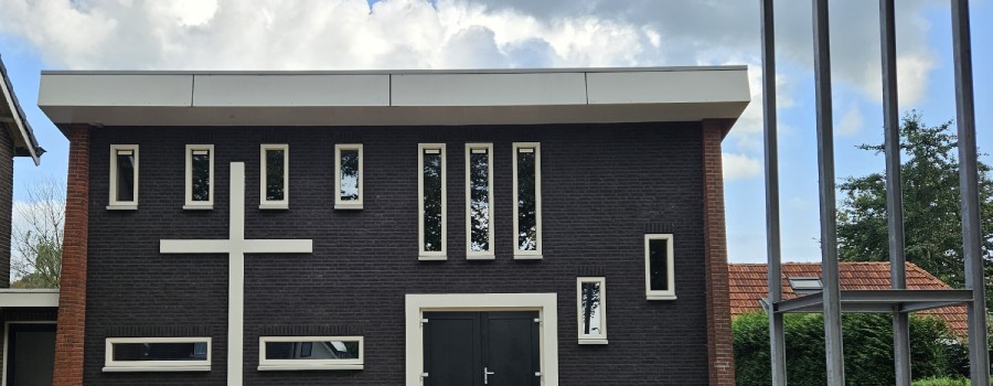 Rechthoekige woning met veel ramen en een kruis op de muur.