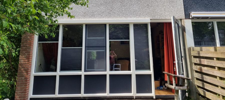 Nieuwbouwwoning met traditionele bakstenen gevel en witte kozijnen en zonnepanelen.