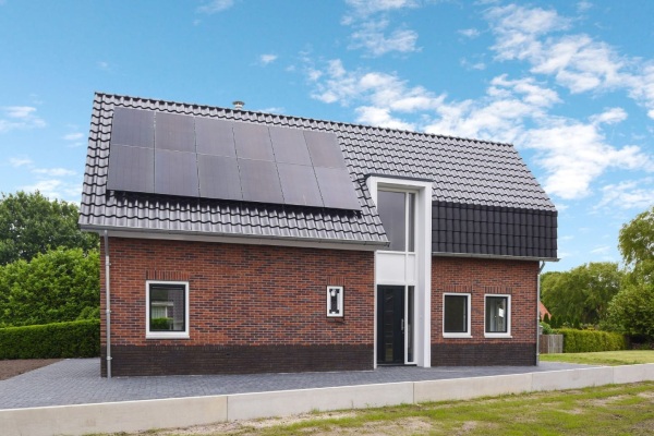 Nieuwbouwwoning met zonnepanelen vanaf zijkant vastgelegd.